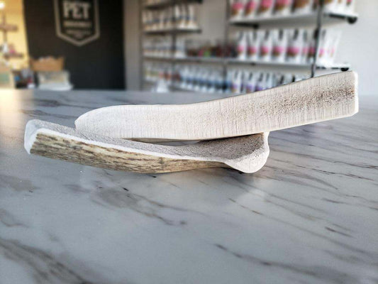Medium split elk antler dog chew laid on marble countertop in pet store background