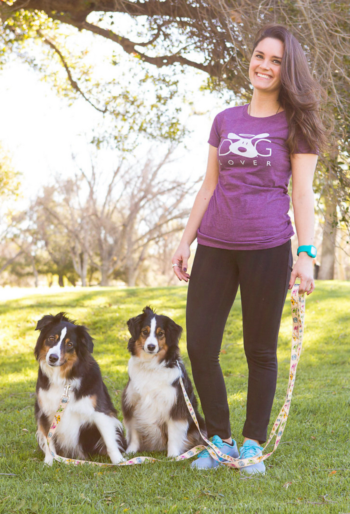 Woman wearing plum Dog Lover T-shirt | Stylish Plum Women's Dog T-shirt for Enthusiasts standing outdoors with two dogs on leashes