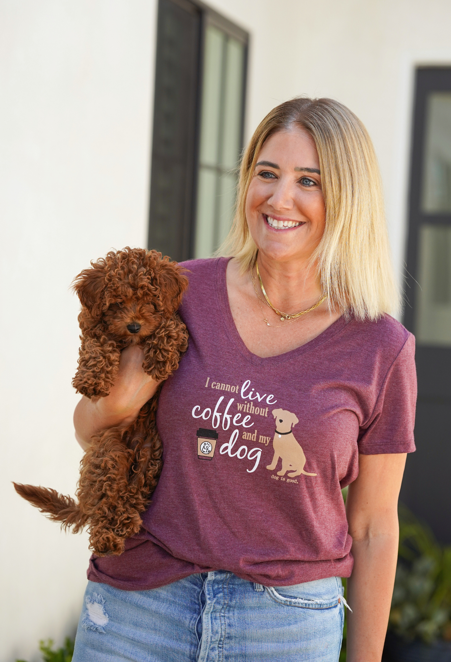 Woman wearing maroon V-neck T-shirt with "I Cannot Live Without Coffee and My Dog" text holding a small brown curly dog