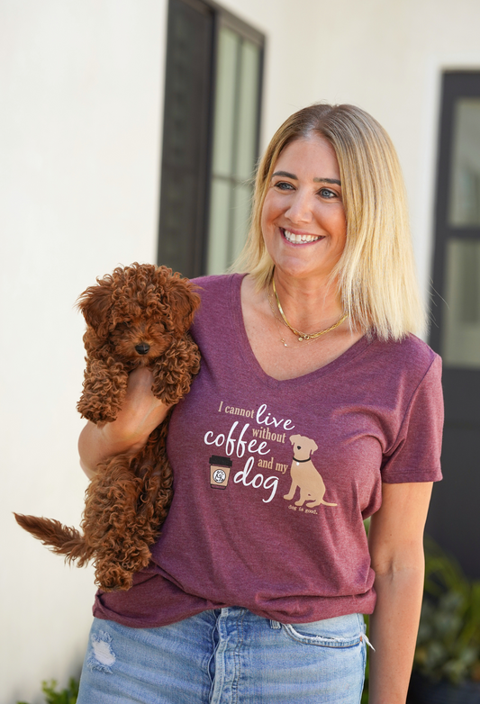 Woman wearing maroon V-neck T-shirt with "I Cannot Live Without Coffee and My Dog" text holding a small brown curly dog