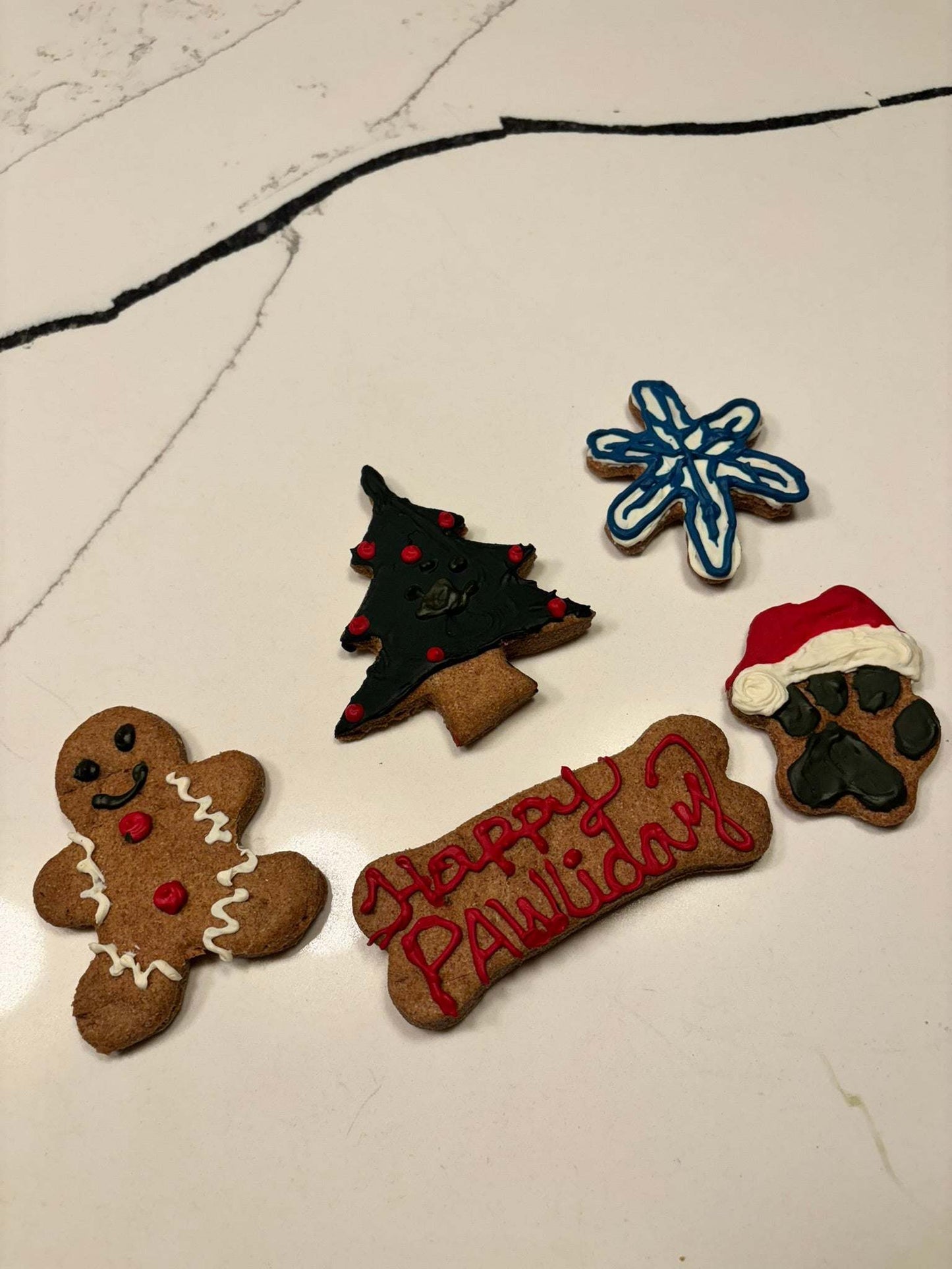 Christmas dog peanut butter cookies in festive shapes including gingerbread, Christmas tree, paw print, snowflake, and bone with "Happy PAWlidays" message