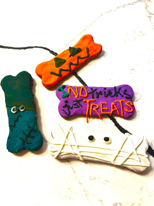 Halloween peanut butter dog cookies shaped like pumpkins, ghosts, and bats in a gift box
