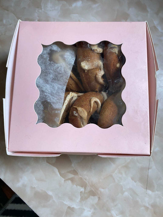 Box of organic peanut butter dog donuts with peanut butter drizzle in pink bakery packaging