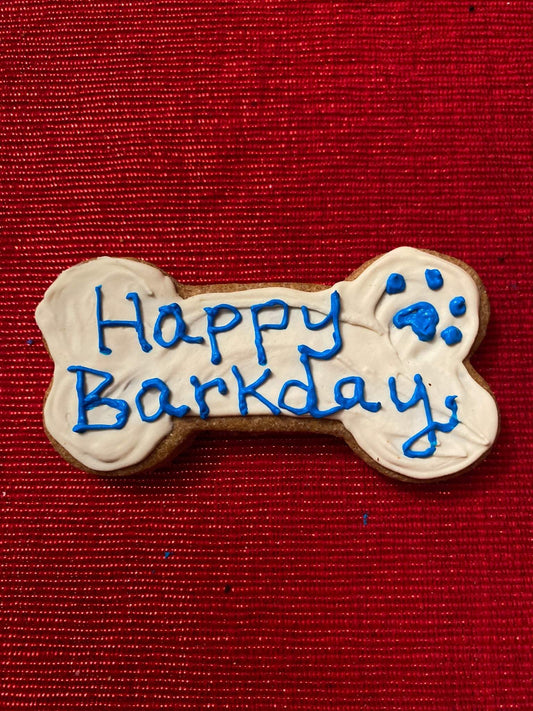 Colorful organic dog cookies shaped like birthday hats, balloons, and cakes in a pink gift box