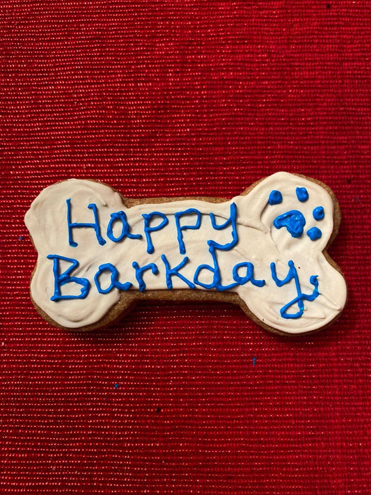 Colorful organic dog cookies shaped like birthday hats, balloons, and cakes in a pink gift box