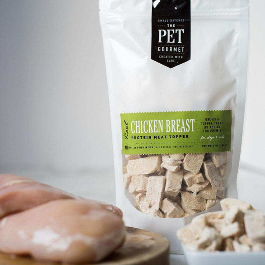 Freeze dried chicken breast dog treat protein meat topper in resealable bag with raw chicken breast nearby