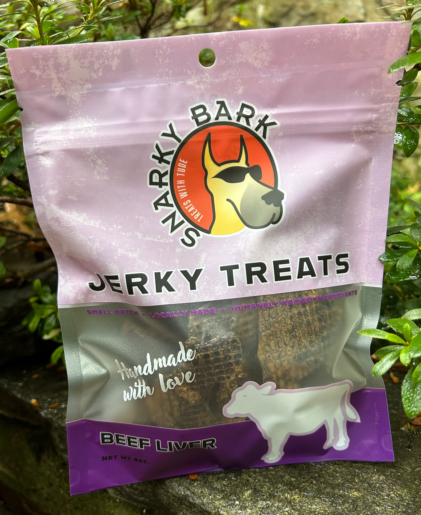 Snarky Bark Beef Liver Jerky dog treats in resealable purple pouch with natural outdoor background