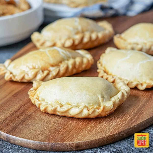 Handmade organic beef EmPAWnadas dog treats with soft whole-wheat pastry on wooden board