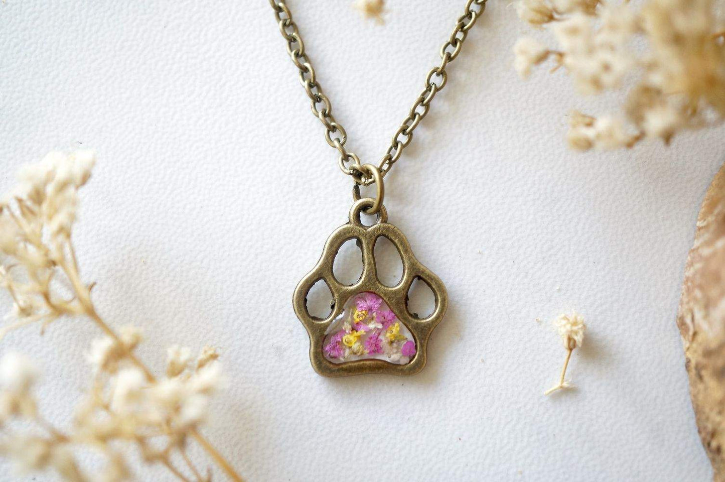 Real dried flowers encased in resin dog paw necklace with pink yellow white petals and bronze frame