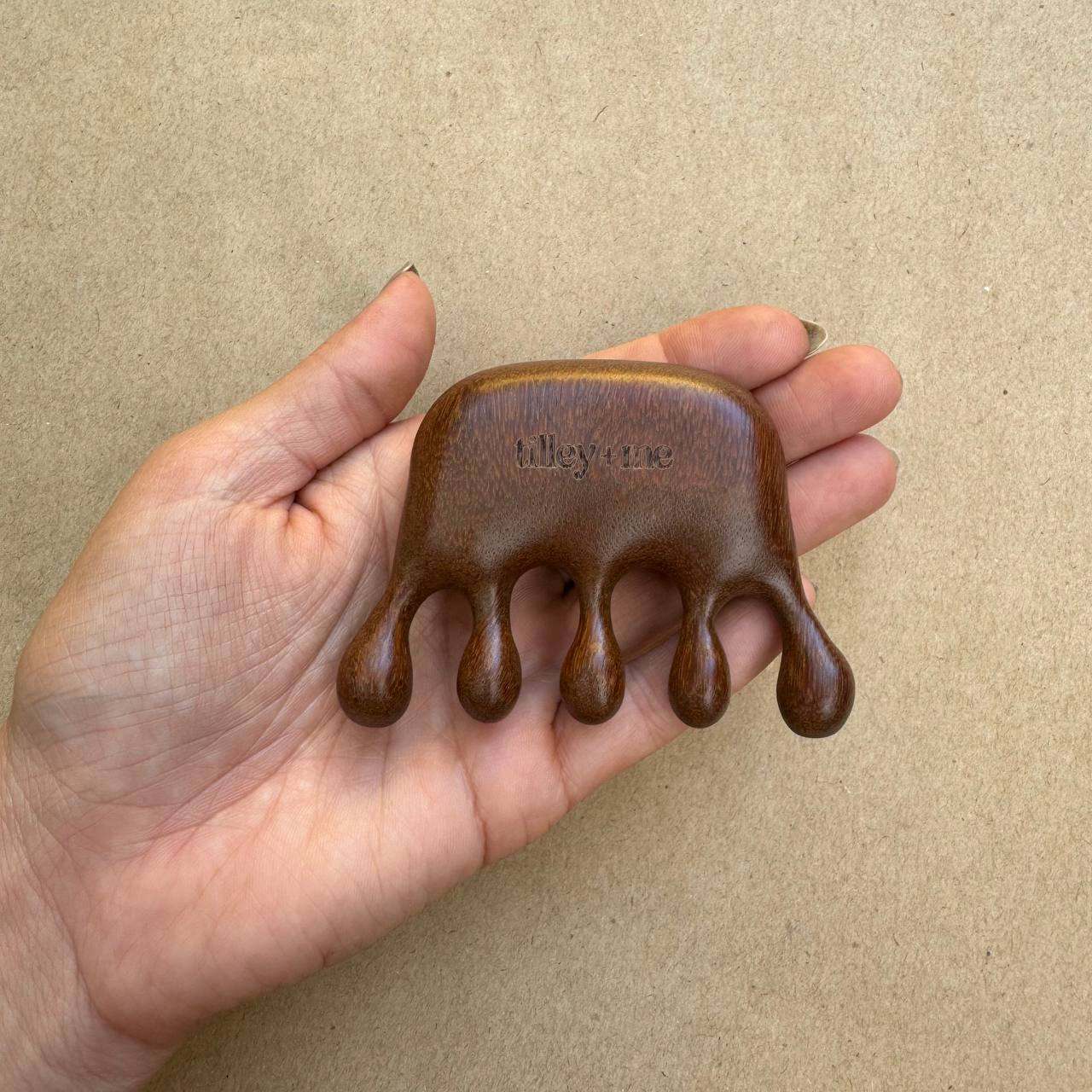 Sandalwood pet massage tool held in hand for shedding relief and circulation boost