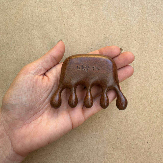 Sandalwood pet massage tool held in hand for shedding relief and circulation boost