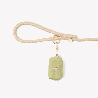 Green poop bag holder pouch clipped to beige dog leash with keyring attachment