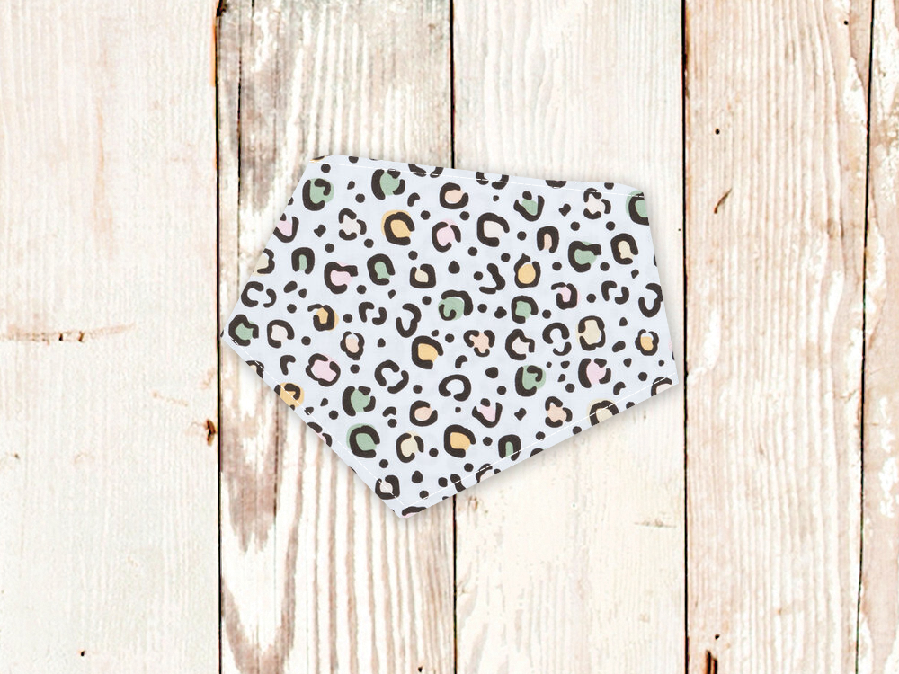 Pastel leopard print dog bandana with snap closures on wooden background