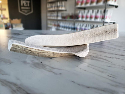 Medium split elk antler dog chew laid on marble countertop in pet store background