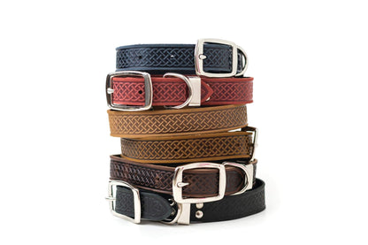 Stack of Celtic style leather dog collars with metal buckles in various colors including black, brown, tan, red, and blue.