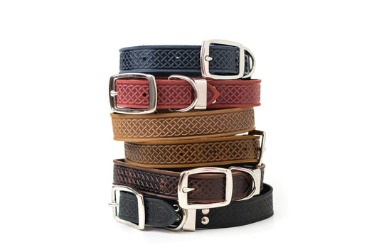 Stack of Celtic style leather dog collars with metal buckles in various colors including black, brown, tan, red, and blue.