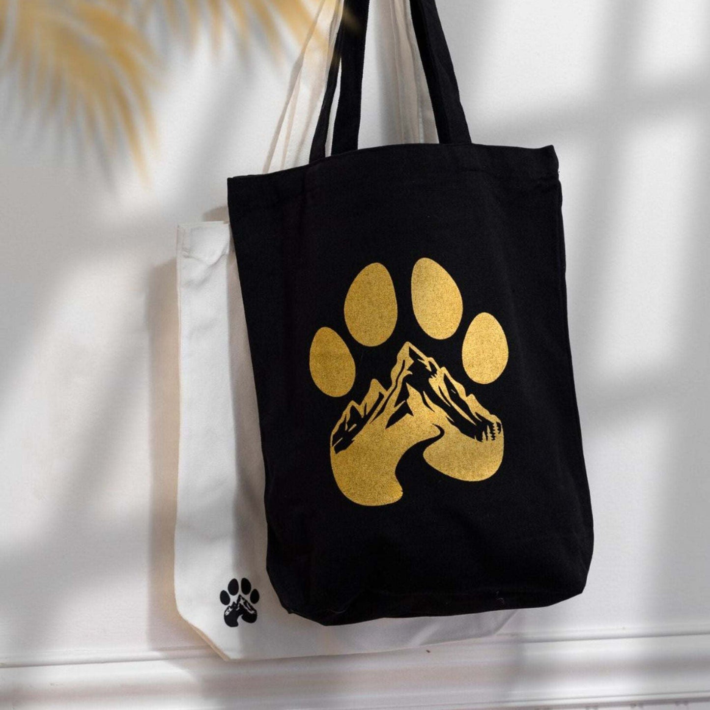 Black Wasatch Pup Tote Bag with gold paw print and mountain design, durable cotton canvas with shoulder straps and interior pocket