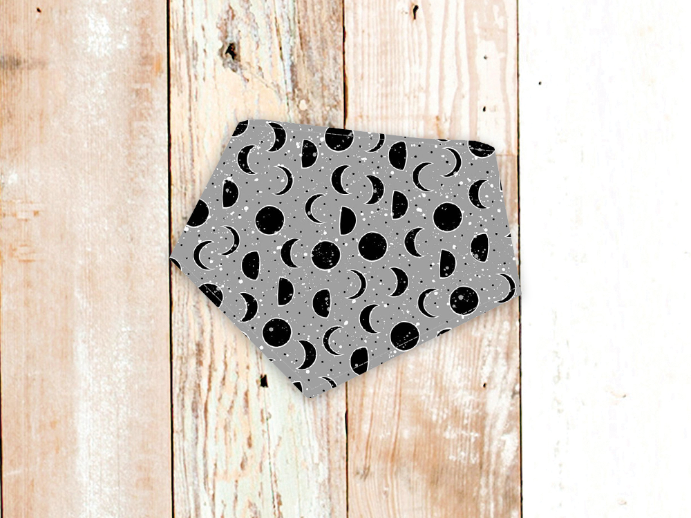 Lunar Grey dog bandana with moon phase pattern and snap closure on wooden background