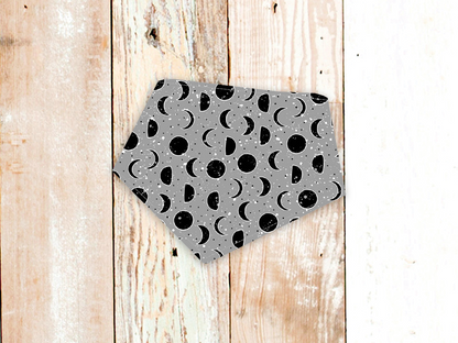 Lunar Grey dog bandana with moon phase pattern and snap closure on wooden background