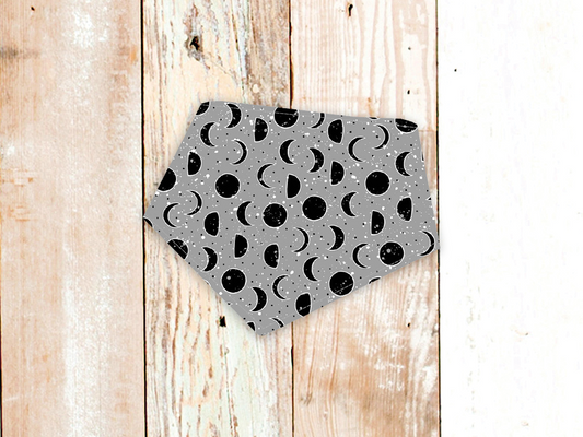 Lunar Grey dog bandana with moon phase pattern and snap closure on wooden background