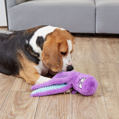 Dog playing with purple octopus-shaped indestructible plush squeaky toy on wooden floor