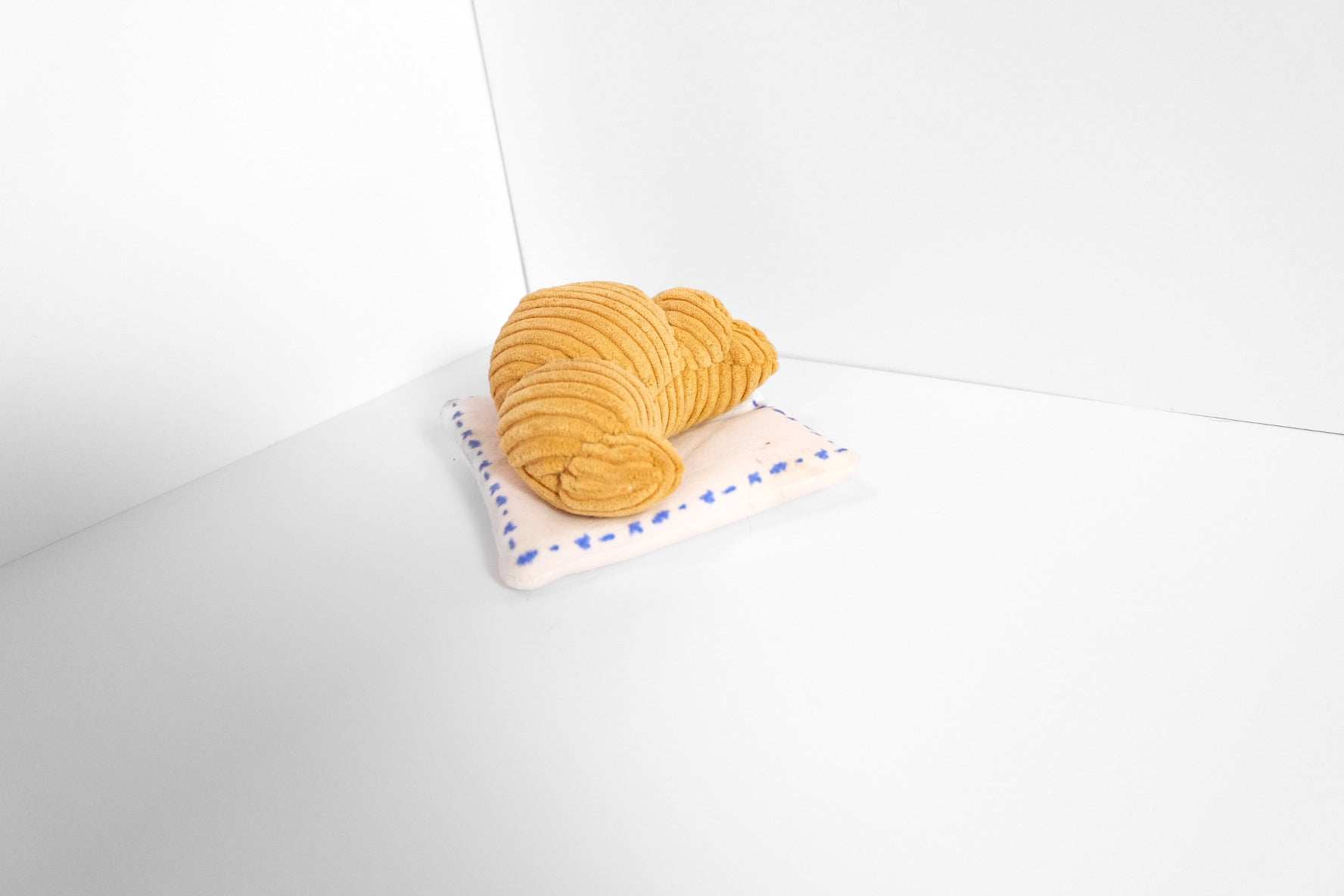 Croissant Nose Work Toy for dogs with squeaker and treat hiding spot on a small pillow