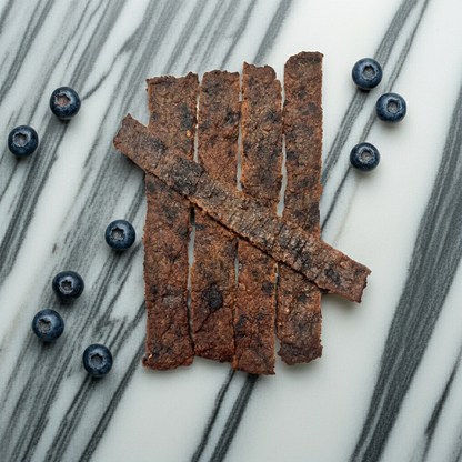 Organic blueberry dog bones treats with fresh blueberries on marble surface
