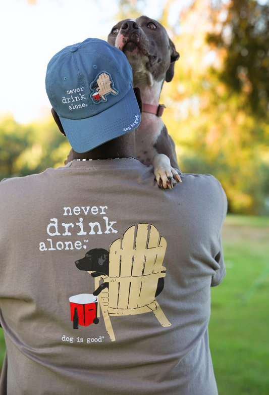 Never Drink Alone T-shirt with dog and chair graphic, grey unisex tee promoting friendship and fun times.
