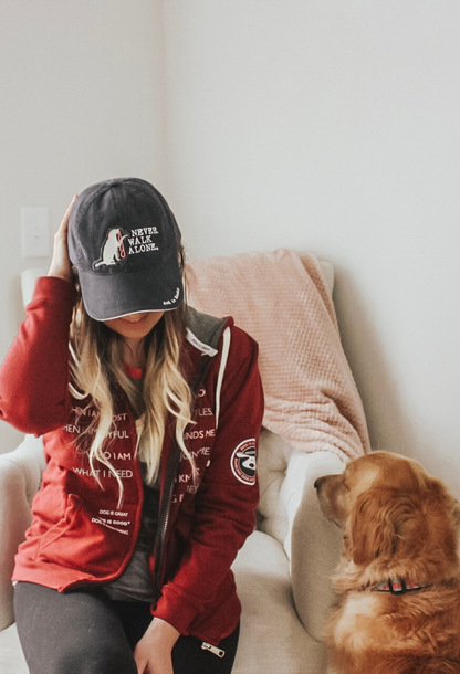 Woman wearing Never Walk Alone Hat with dog sitting beside her indoors