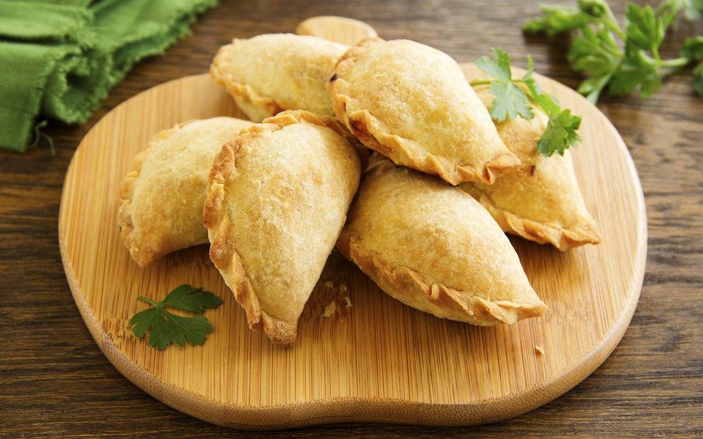 Organic beef EmPAWnadas dog treats with soft whole wheat pastry and fresh herbs on wooden board