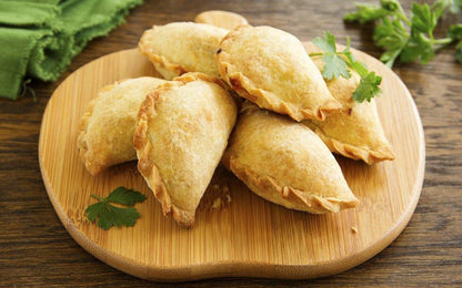 Organic beef EmPAWnadas dog treats with soft whole wheat pastry and fresh herbs on wooden board