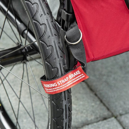 Close-up of parking strap brake on red 2-in-1 pet bike trailer stroller wheel