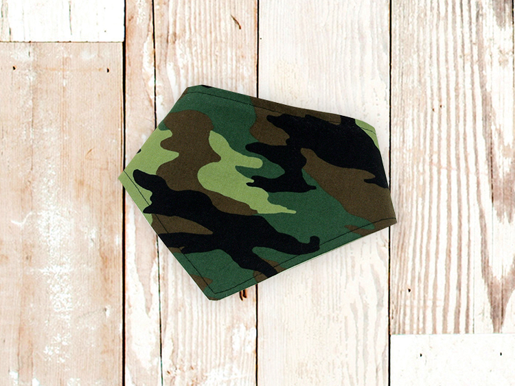 Green camouflage dog bandana with adjustable snap closures on wooden background
