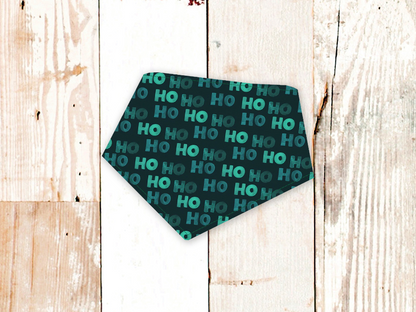 Green HoHoHo dog bandana with adjustable snap closures and flannel backing on wooden background