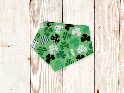 Green Shamrocks Dog Bandana with adjustable snap closures and white flannel backing on wooden surface