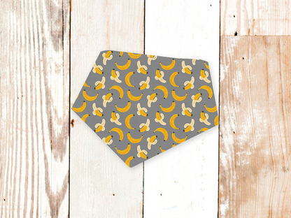Grey Bananas Dog Bandana with yellow banana pattern and adjustable snap closures on grey background