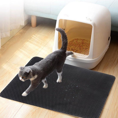 Gray honeycomb cat litter pad with waterproof EVA foam and quilted edges under a white cat litter box with a gray cat stepping on it