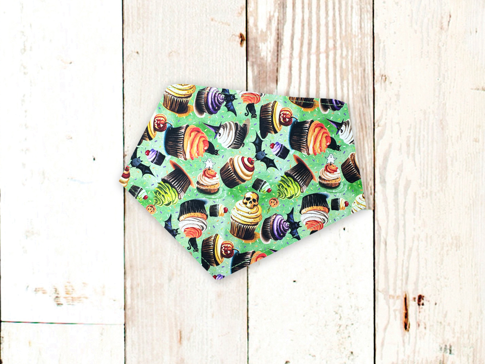 Halloween cupcakes patterned dog bandana with adjustable snap closures and white flannel backing on wooden background