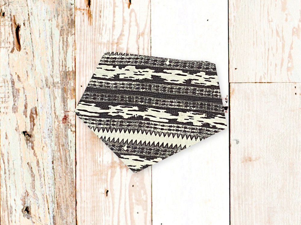 Black and white patterned adjustable dog bandana with snap closures on wooden background