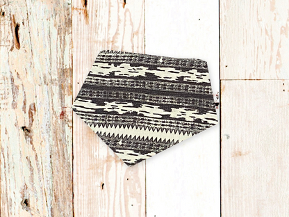 Black and white patterned adjustable dog bandana with snap closures on wooden background