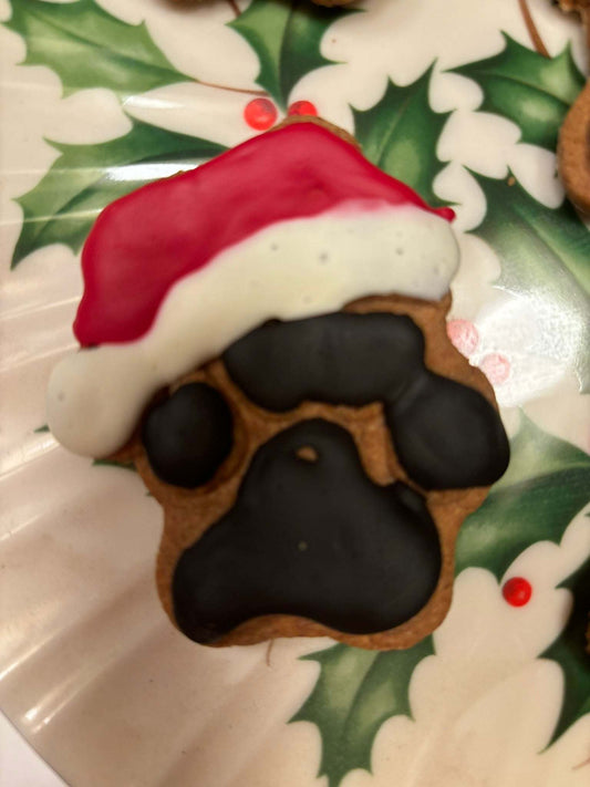 Santa Paws Organic Peanut Butter Dog Treat shaped like Santa's paw with festive red and white icing on holiday plate