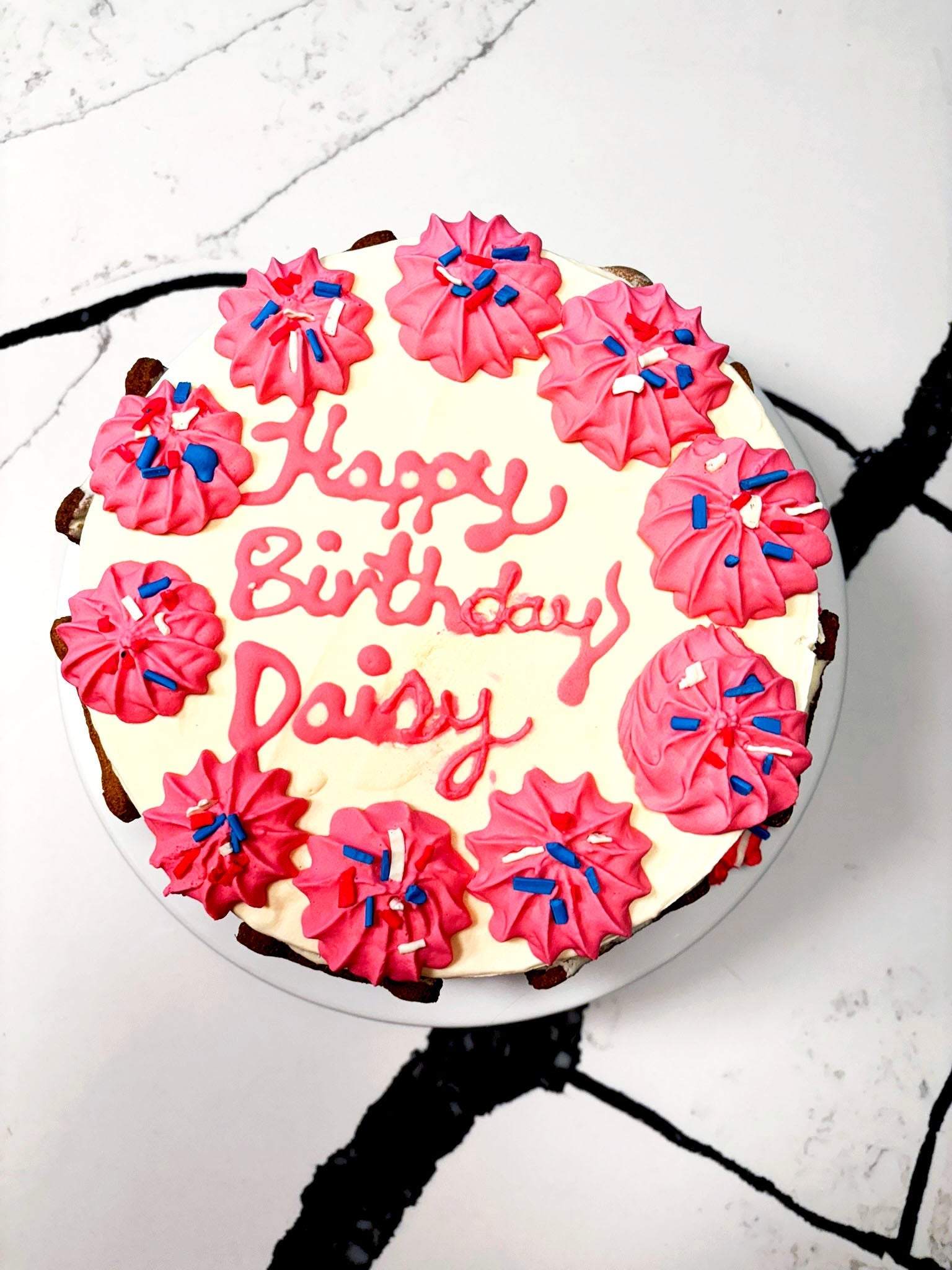 Organic dog birthday cake with pink frosting and sprinkles, personalized for Daisy