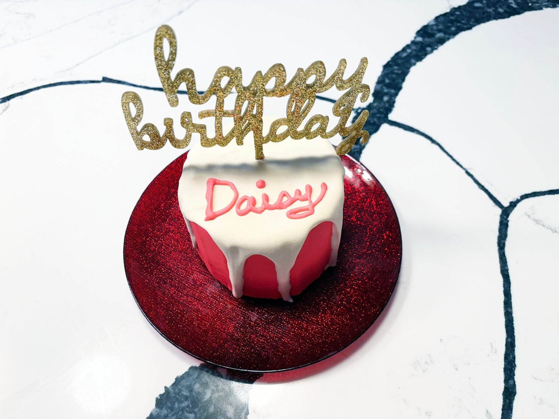 Organic dog birthday gotcha cake with pink and white frosting and gold glitter happy birthday topper