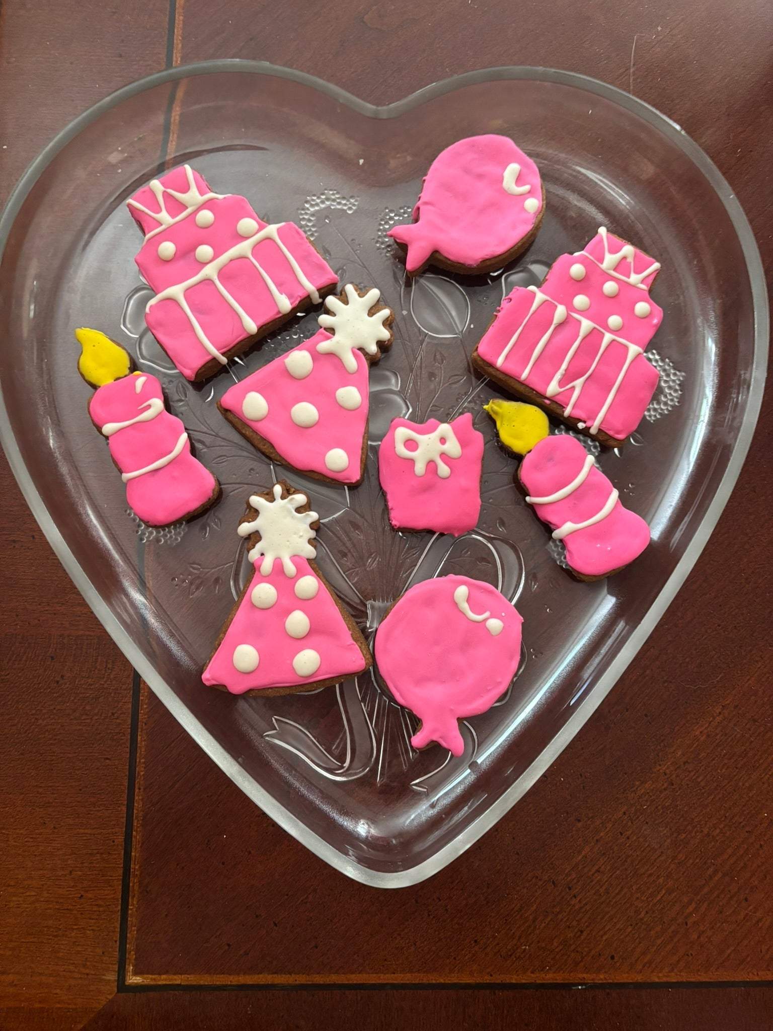 Birthday Girl Organic Dog Cookies in pink birthday-themed shapes on a heart-shaped plate