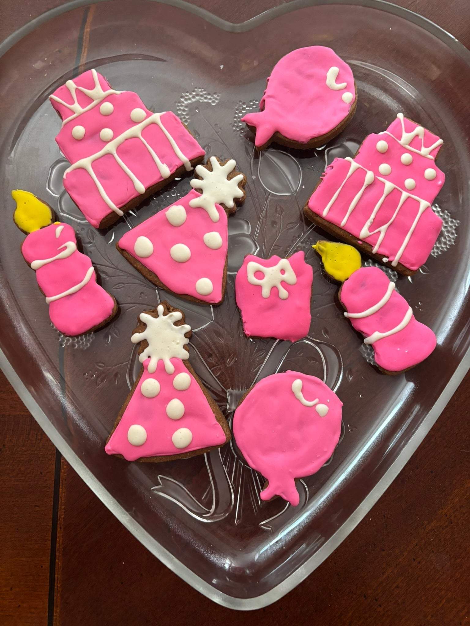 Birthday Girl Organic Dog Cookies in pink birthday-themed shapes on a heart-shaped glass plate