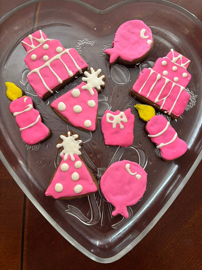 Birthday Girl Organic Dog Cookies in pink birthday-themed shapes on a heart-shaped glass plate