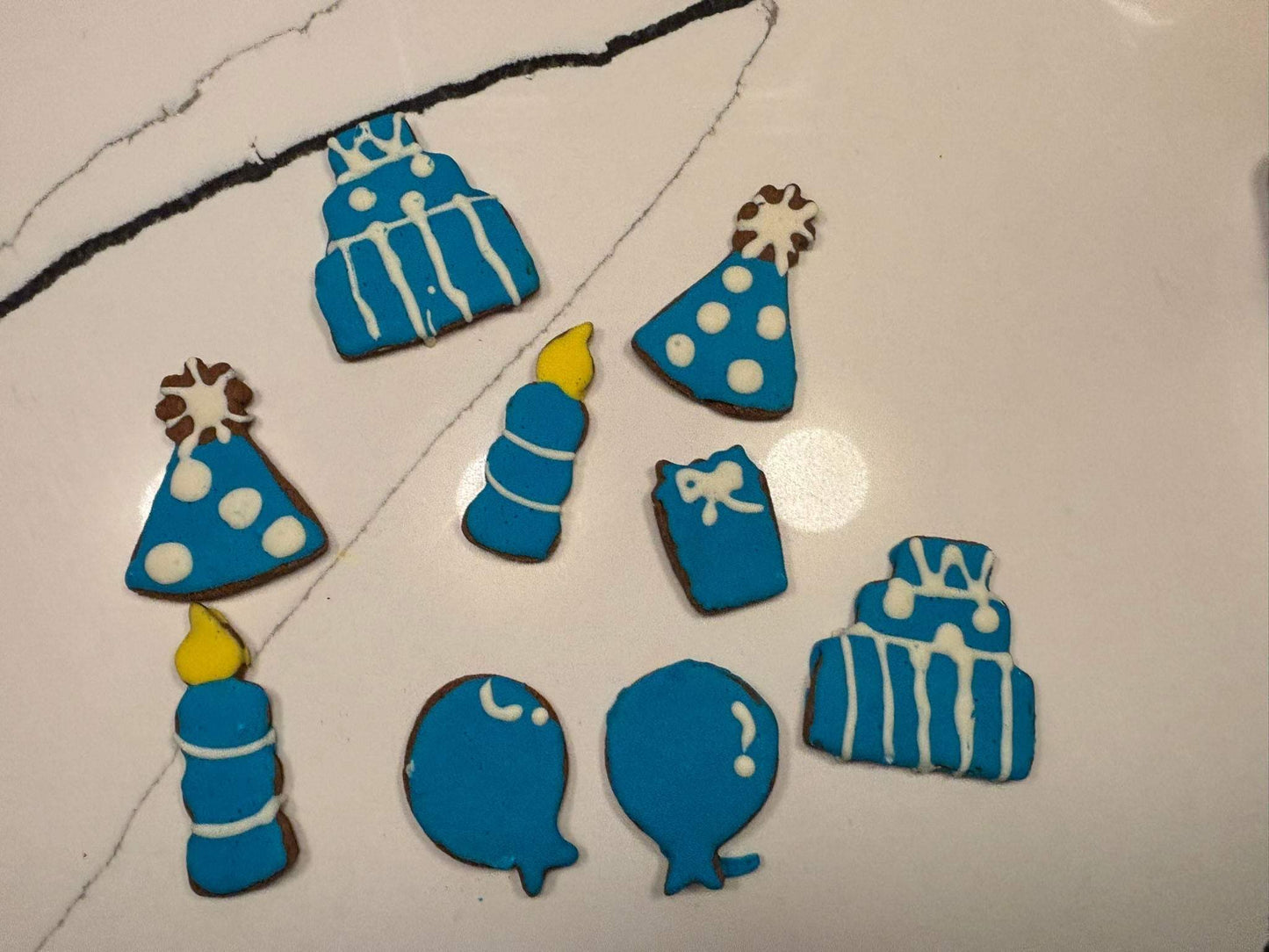 Birthday Boy Organic Dog Cookie Box with blue and white birthday-themed peanut butter dog cookies in shapes of cakes, hats, candles, balloons, and gifts