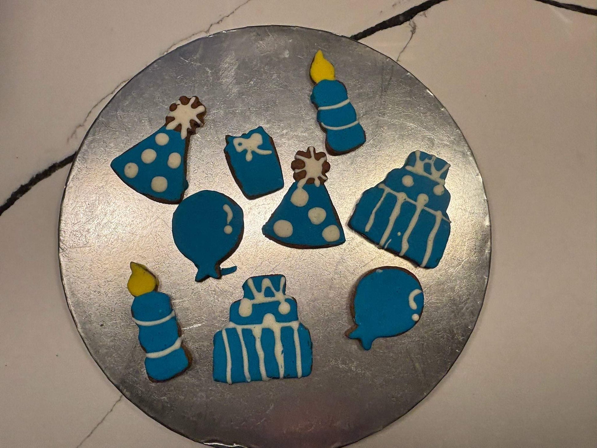 Birthday Boy Organic Dog Cookie Box with blue and white birthday-themed dog cookies including balloons, candles, hats, and cakes on a round silver plate