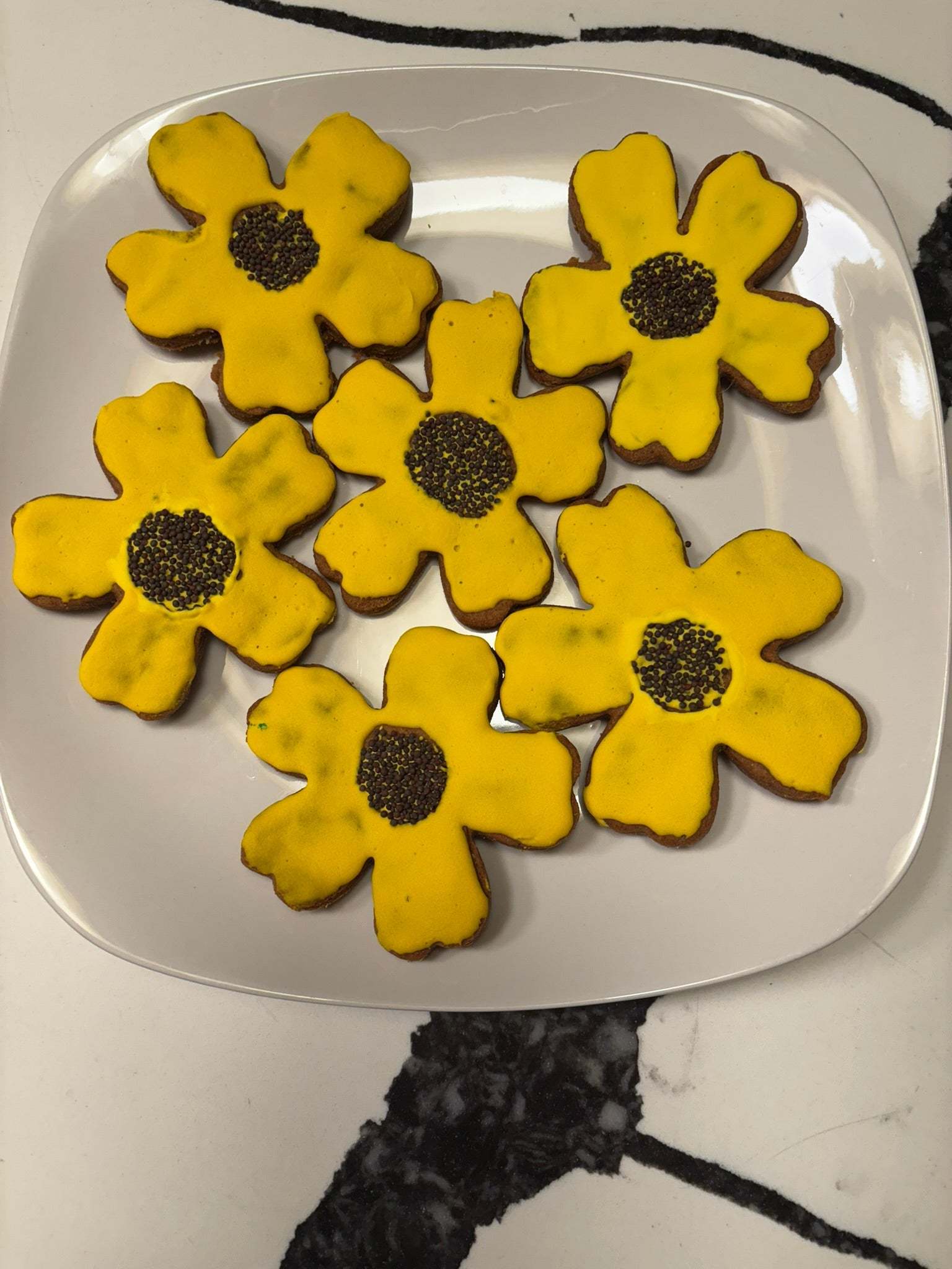 Organic Sunflower Peanut Butter Cookies with yellow glaze and black sesame seed centers on white plate