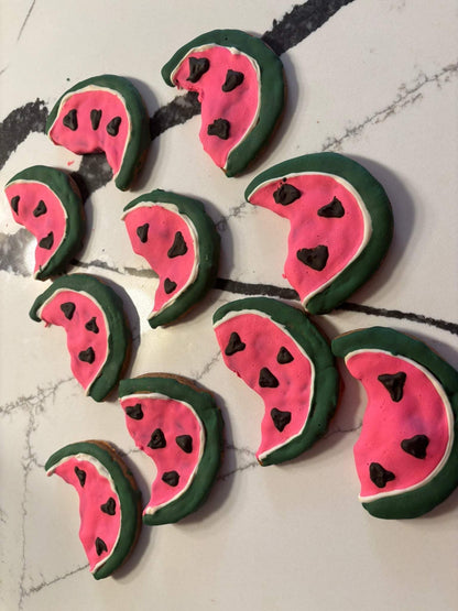Organic watermelon dog cookies shaped like watermelon slices with green and pink icing and chocolate chip seeds
